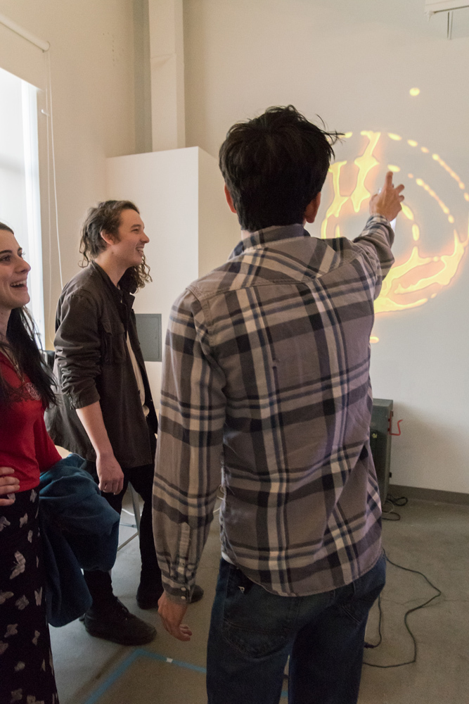 Students laughing and playing with digital light drawing tools in the Make+Think+Code technology and research lab at Pacific Northwest College of Art (PNCA).