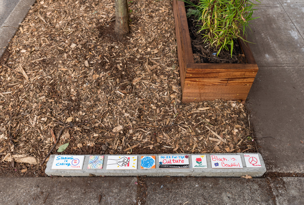 A set of tiles featuring an array of artwork near a planter box