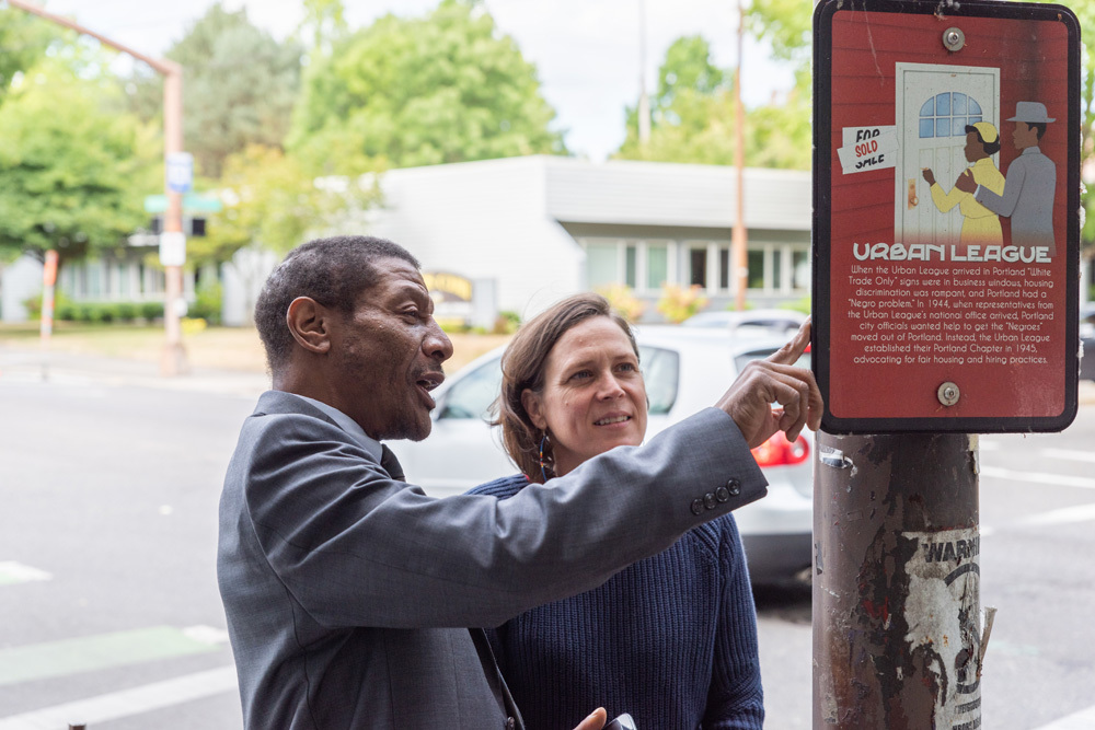 Two people reading a sign about the Urban League