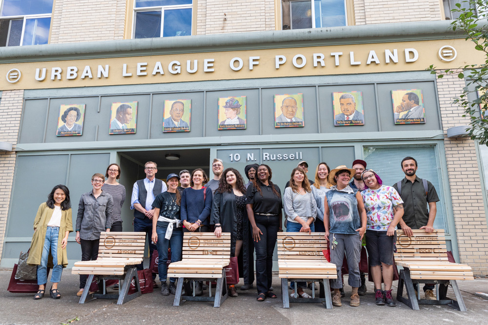 A photo of individual benches and the artists that created them outside of the Urban League of Portland