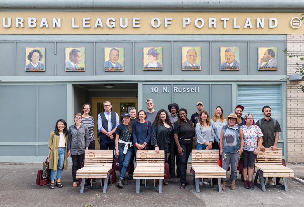 A group of artists standing outside individual homemade benches outside of the Urban League of Portland