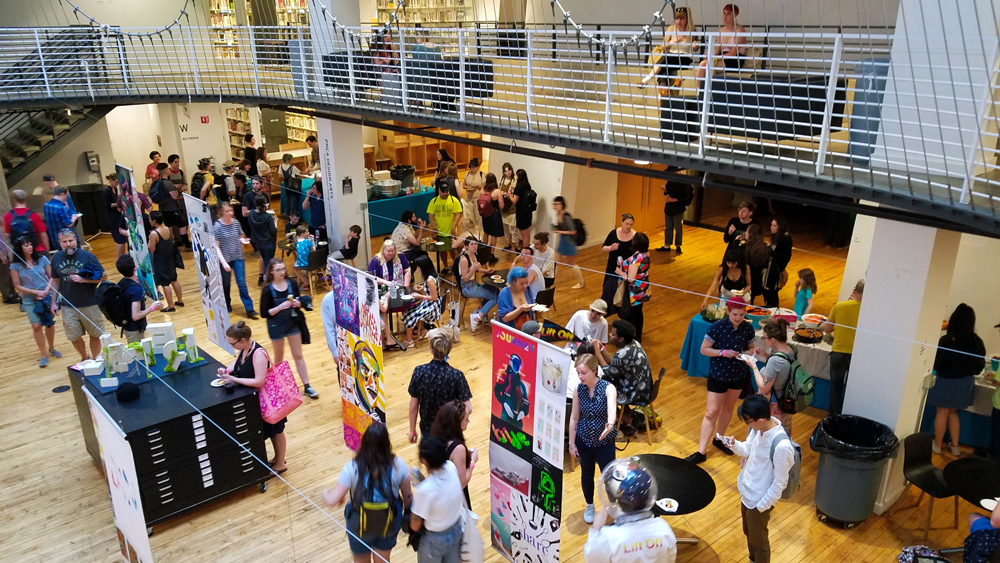 Pacific Northwest College of Art (PNCA) Design arts Senior Portfolio show (design displays of graphic art work) arranged in our open atrium with crowds of people viewing.