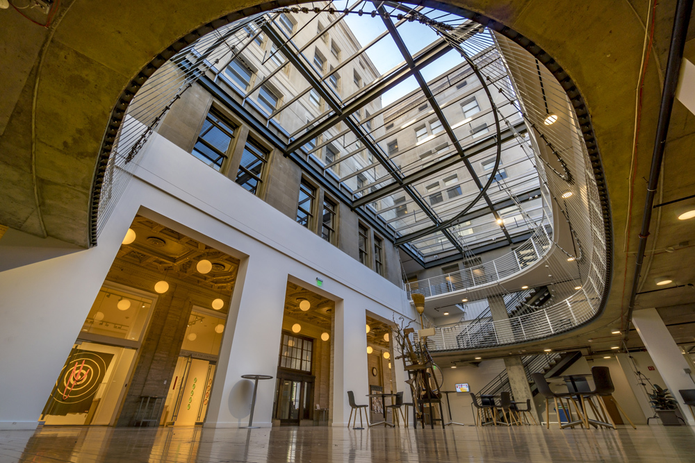 Pacific Northwest College of Art (PNCA) atrium, a three-story contemporary space with concrete mezzanine with cable supports, a restored wooden floor, and ceiling of skylights.