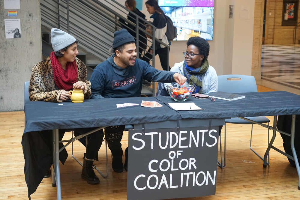 Students of Color Coalition Club table with club members sitting and with other Pacific Northwest College of Art (PNCA) students about their club.
