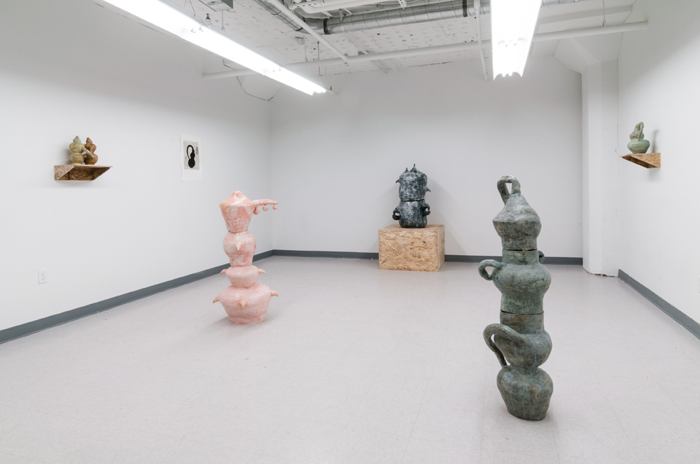 Several pink, grey, and green sculptures around a room stacked on top of each other