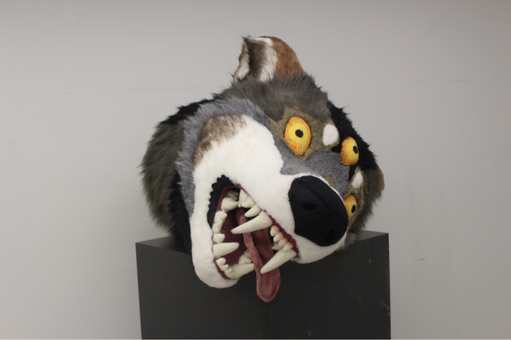 Artwork of a wolf head with three eyes and a tongue falling out of its mouth