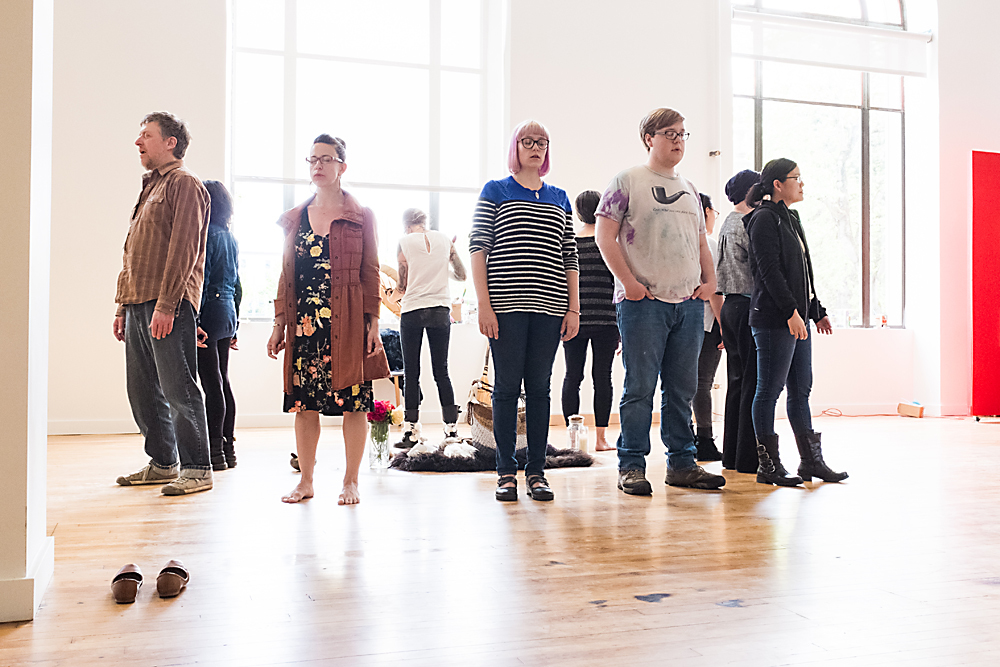 People standing in a circle facing away from each other in an art studio