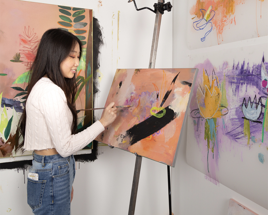 A PNCA student painting an abstract pink canvas